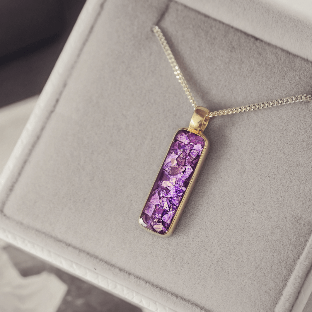 9ct yellow gold necklace with a purple setting on a gray surface