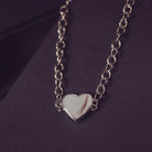 Silver heart-shaped bracelet on a dark purple background