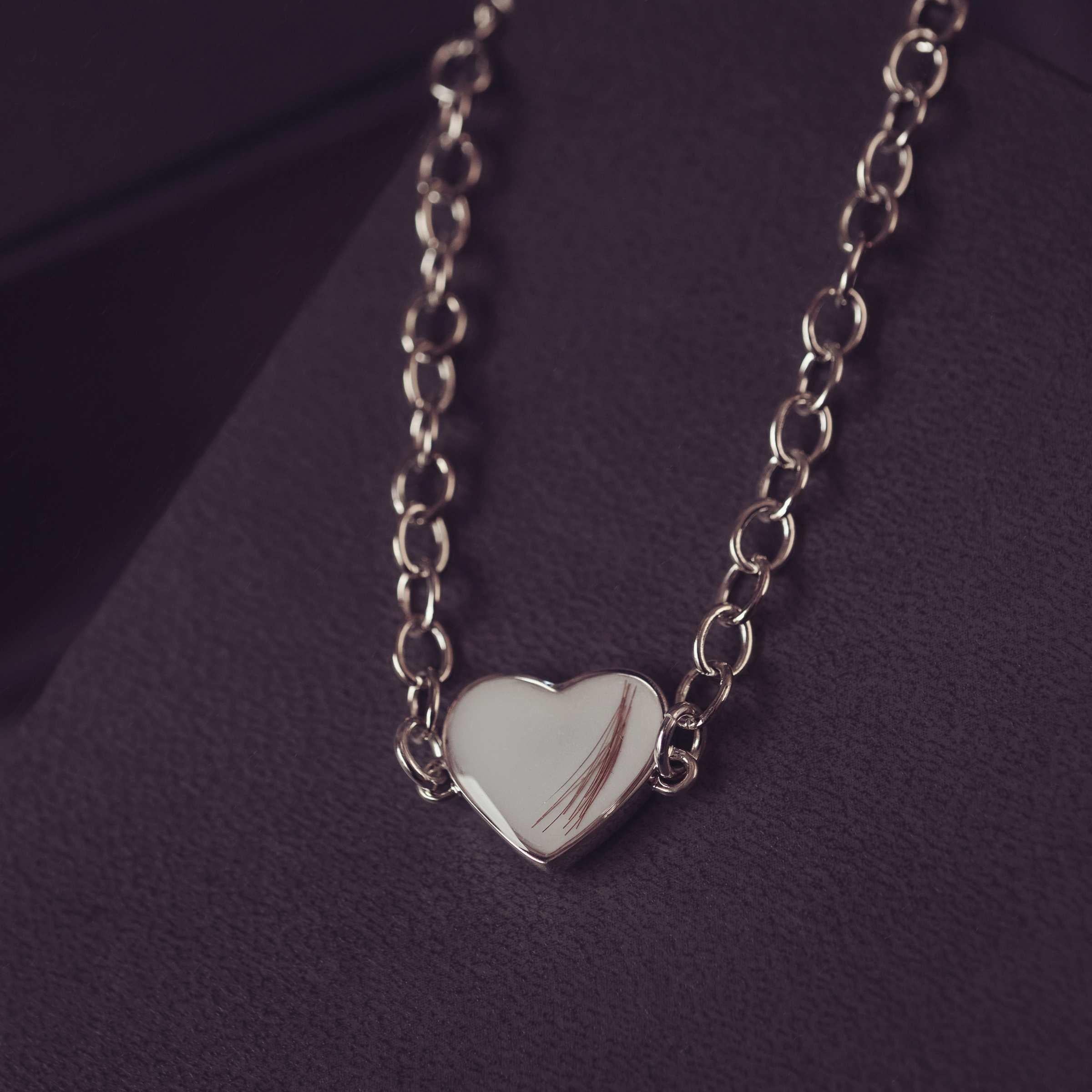 Silver heart-shaped bracelet on a dark purple background