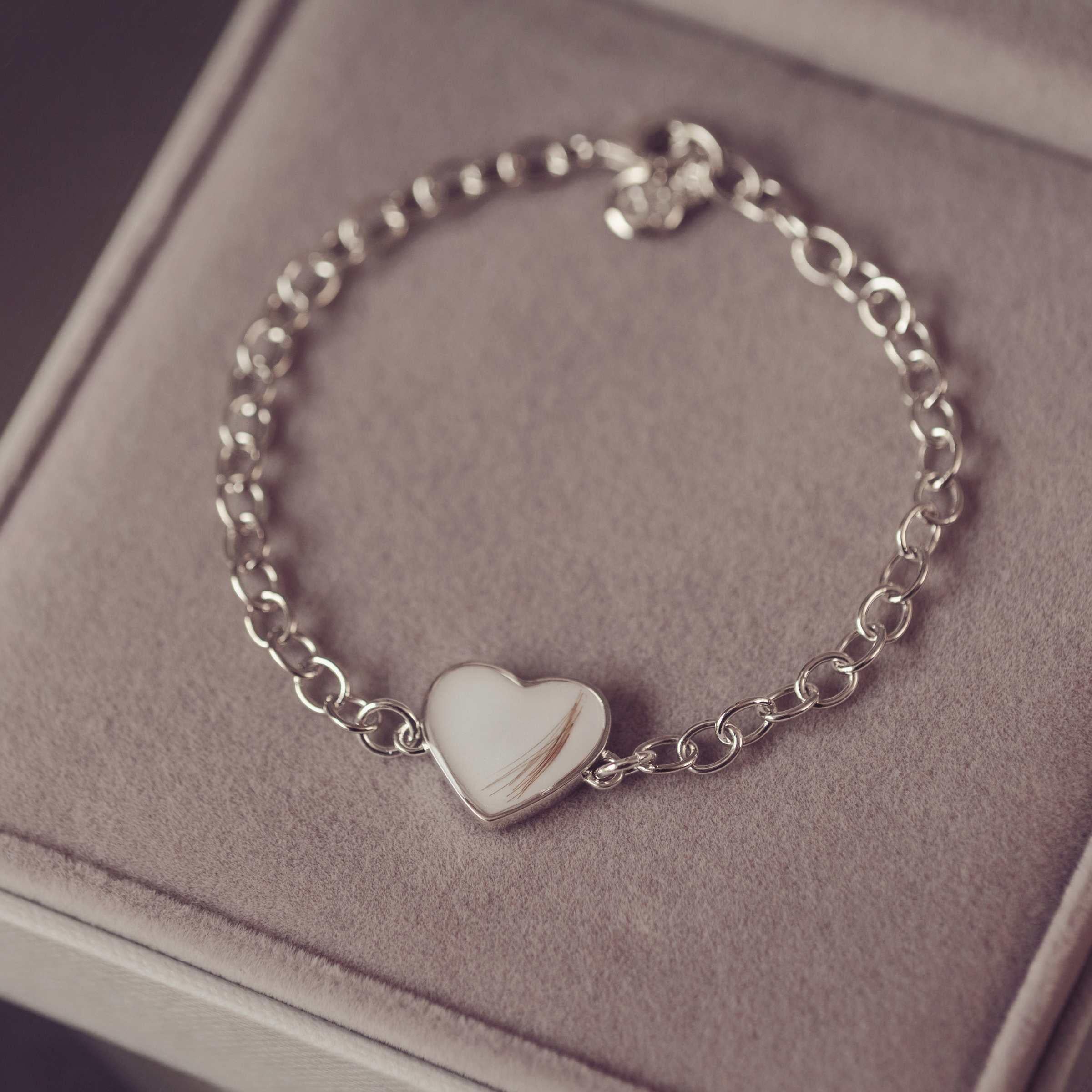 Silver bracelet with a heart-shaped charm on a soft surface