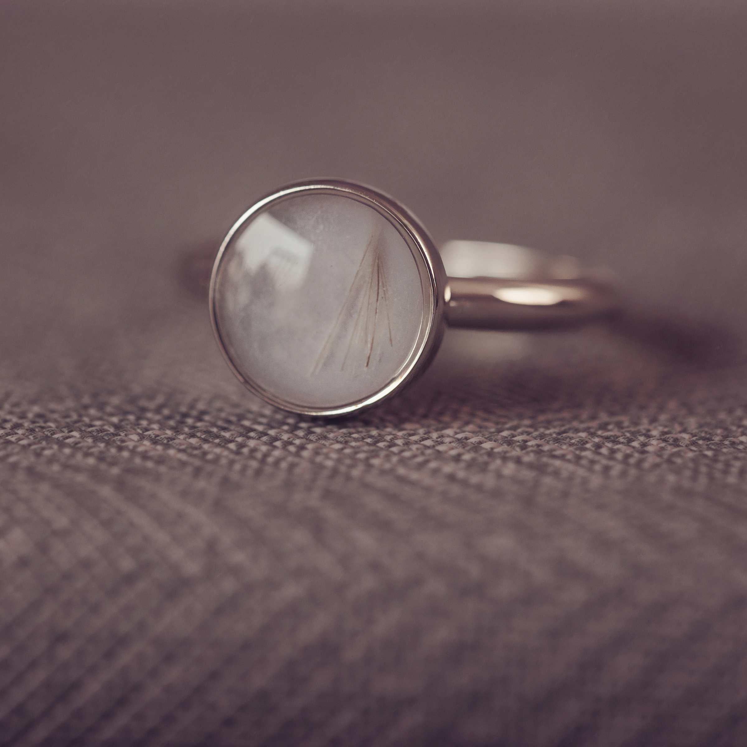 Silver ring with a circular ring on a textured brown surface