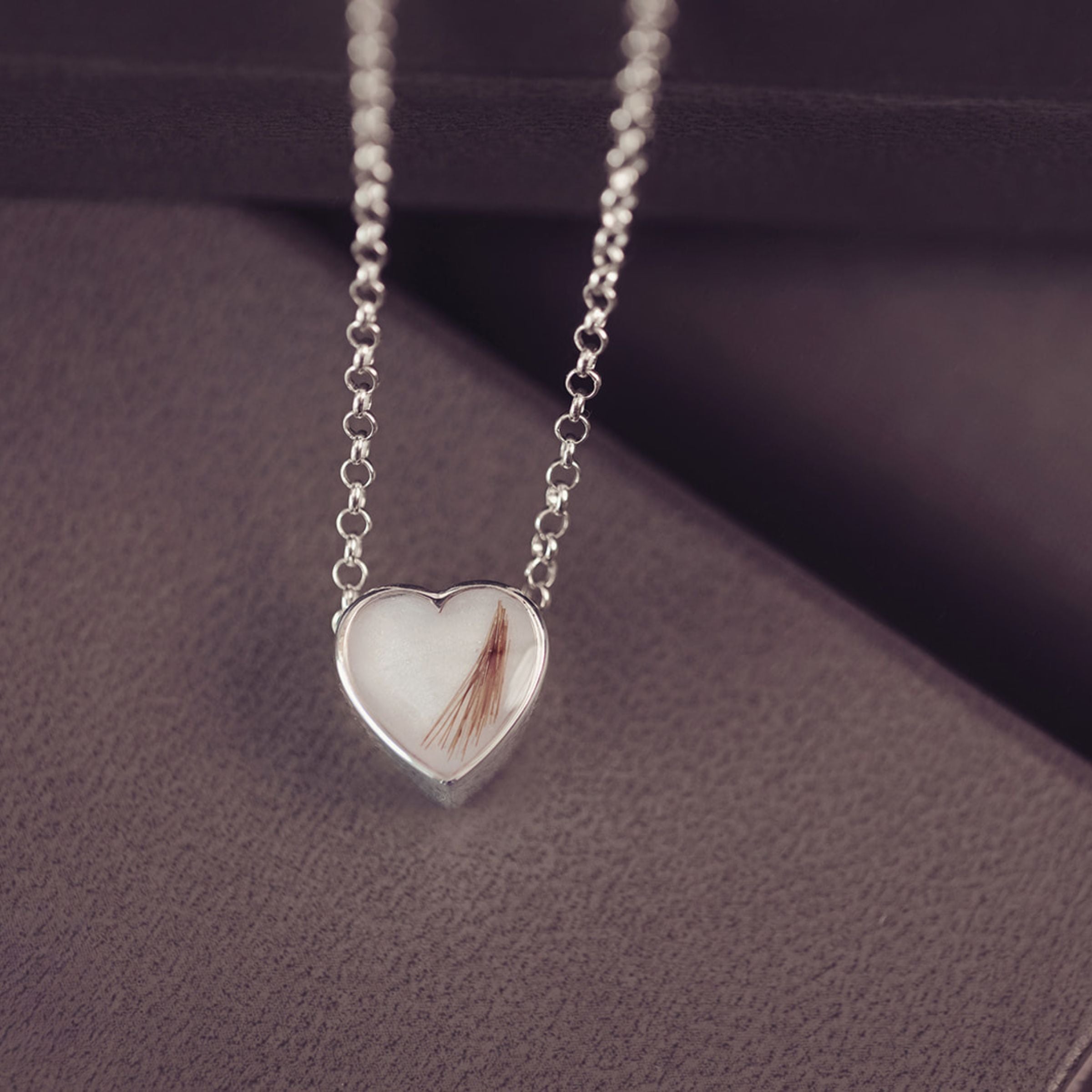 Heart-shaped silver pendant necklace on a textured surface