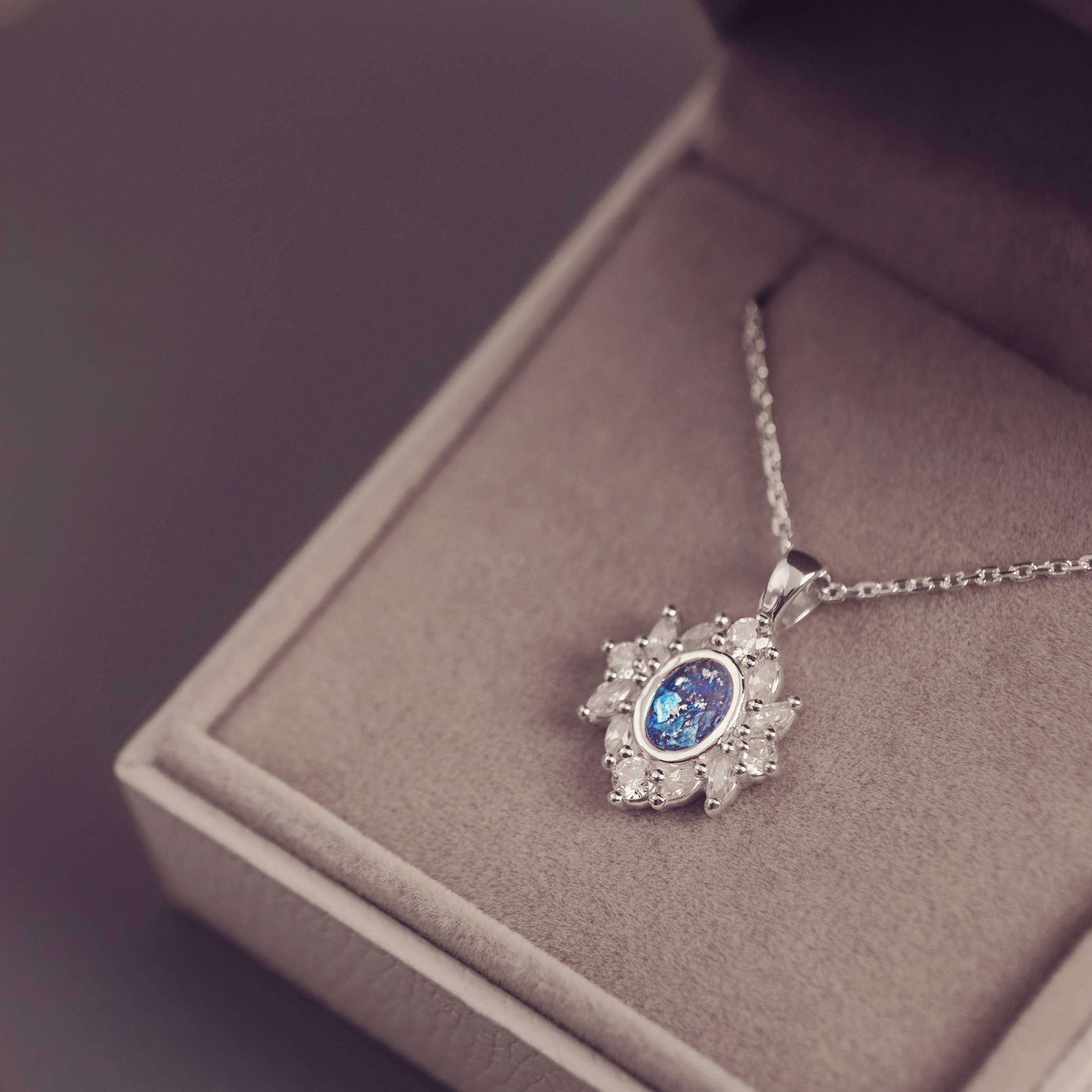 Silver necklace with a blue gemstone pendant on a gray surface