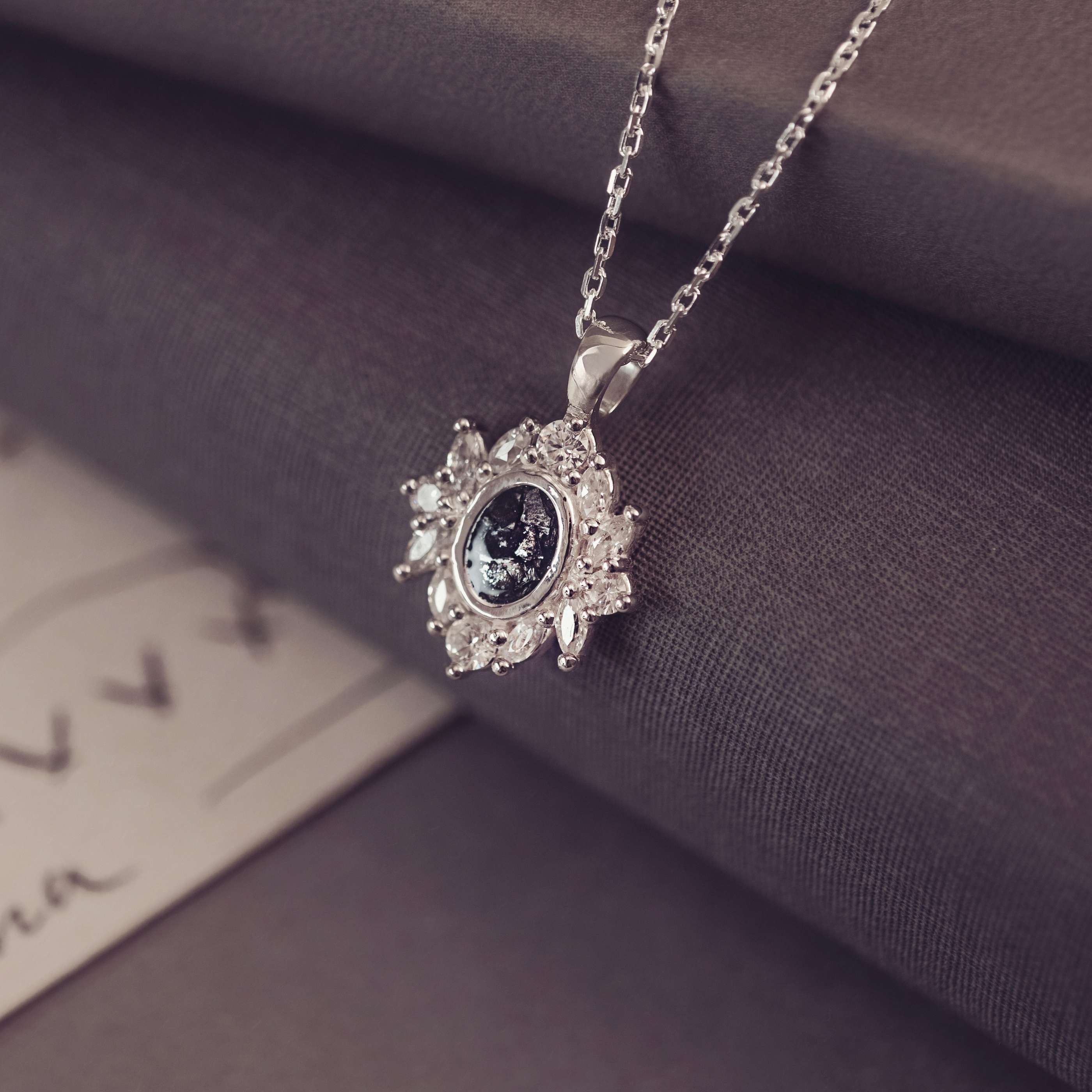 Silver necklace with a decorative pendant on a textured surface