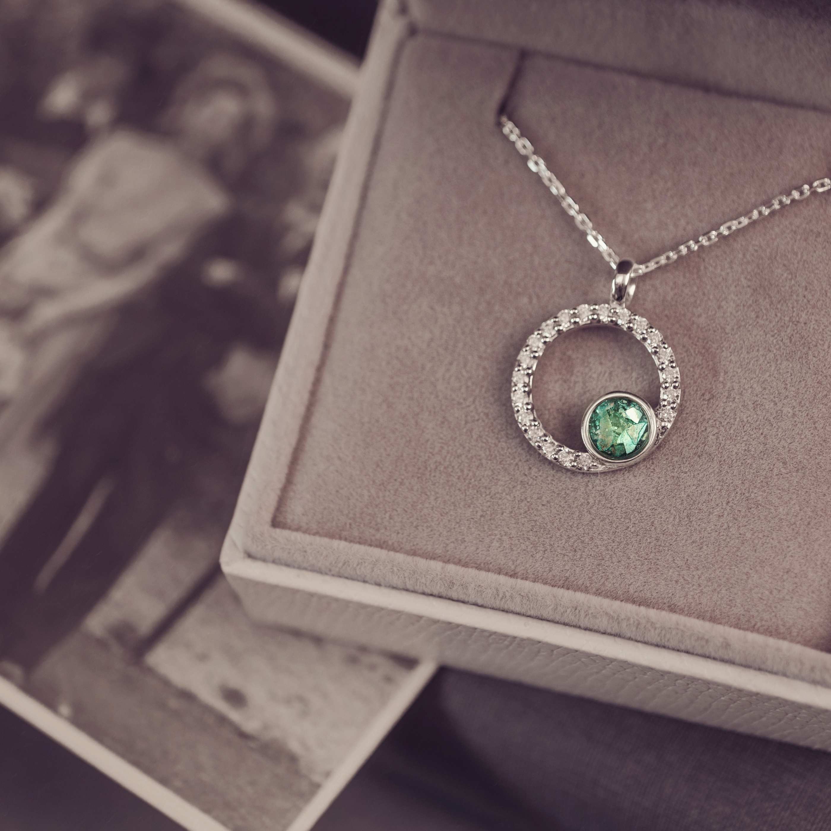 Silver necklace with a green gemstone pendant on a jewelry box.