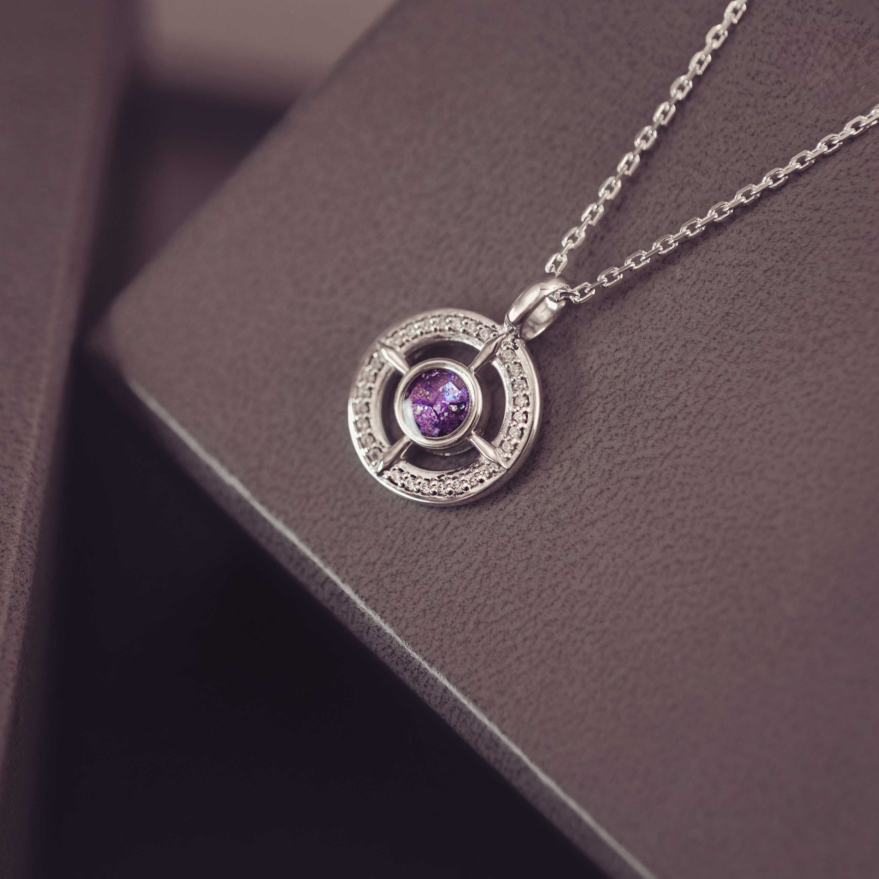 Silver necklace with a purple gemstone pendant on a dark surface