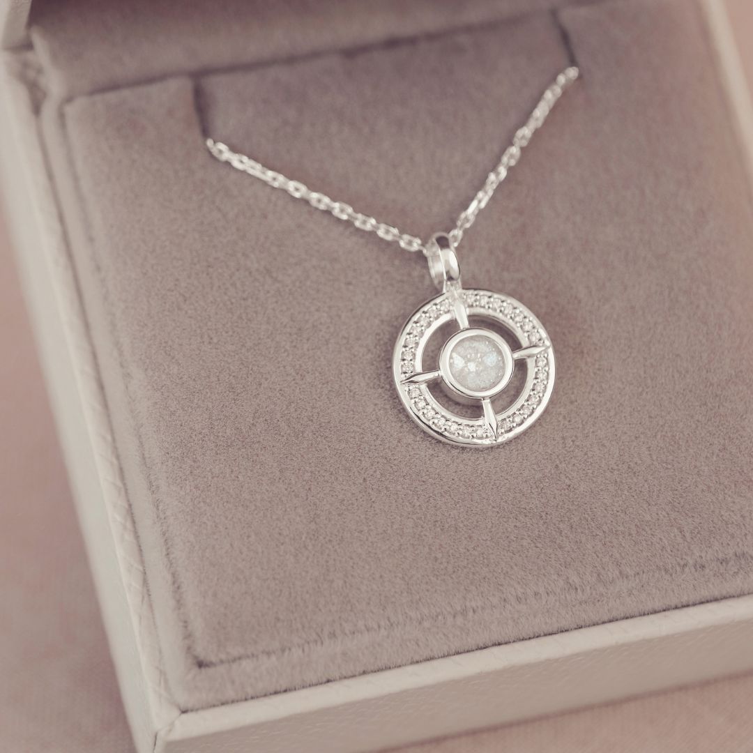 Silver necklace with a circular pendant on a pink jewelry box