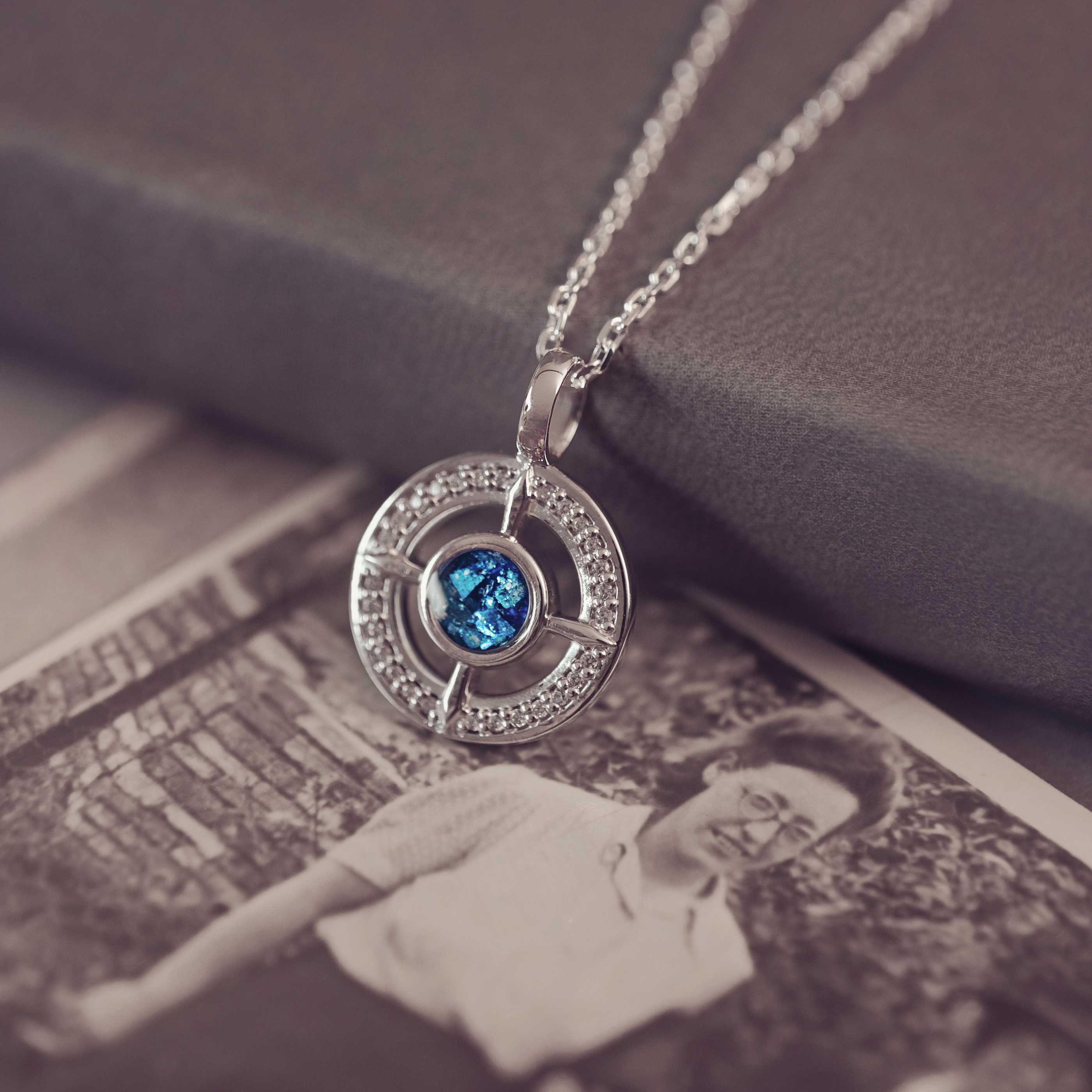 Silver necklace with a blue gemstone pendant on a vintage book