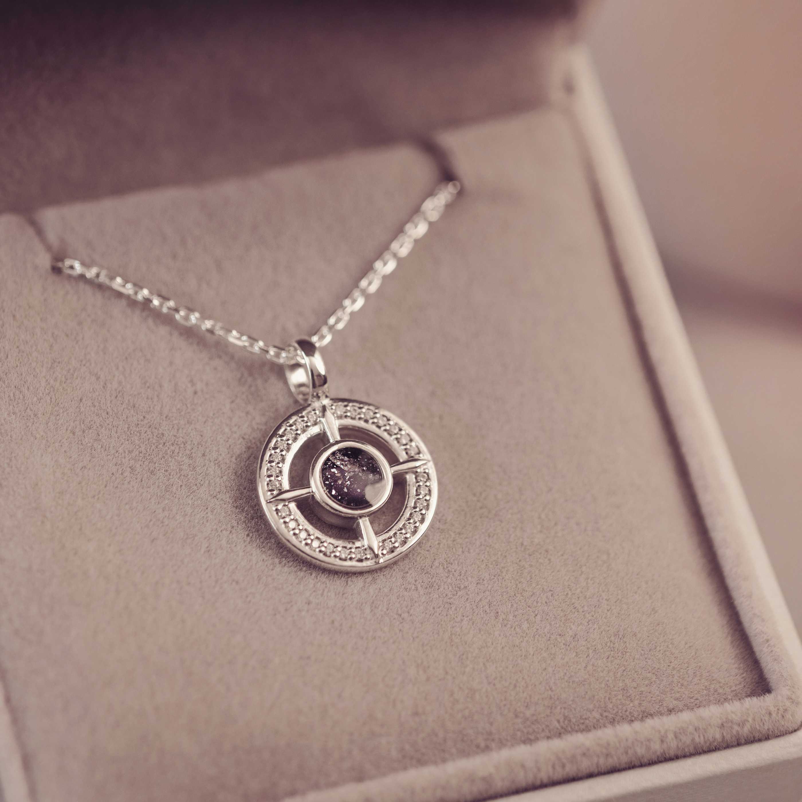 Silver necklace with a circular pendant on a soft surface