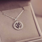Silver necklace with a circular pendant on a soft surface