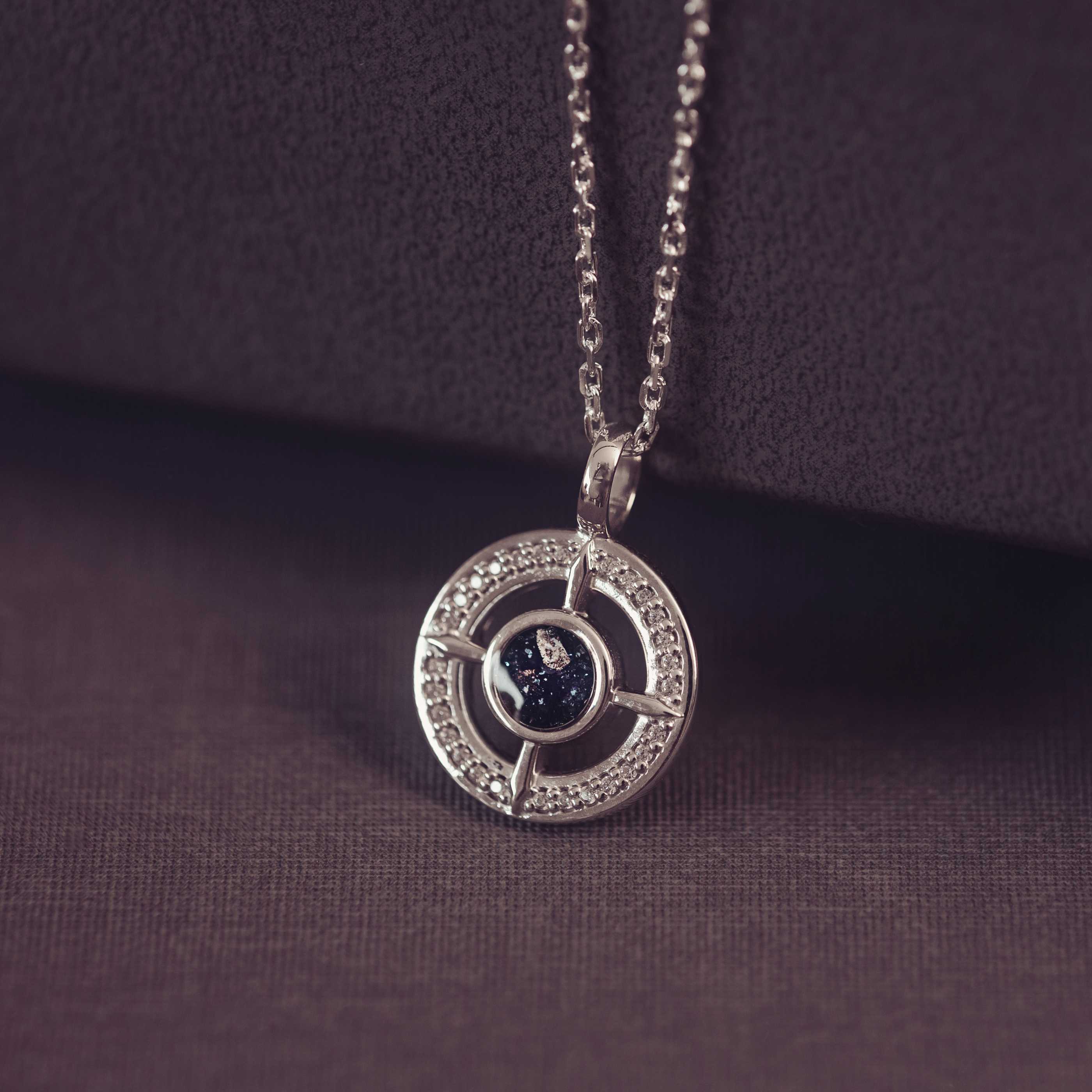 Silver necklace with a circular pendant on a dark purple background