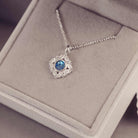 Silver necklace with a blue gemstone pendant on a gray cushion