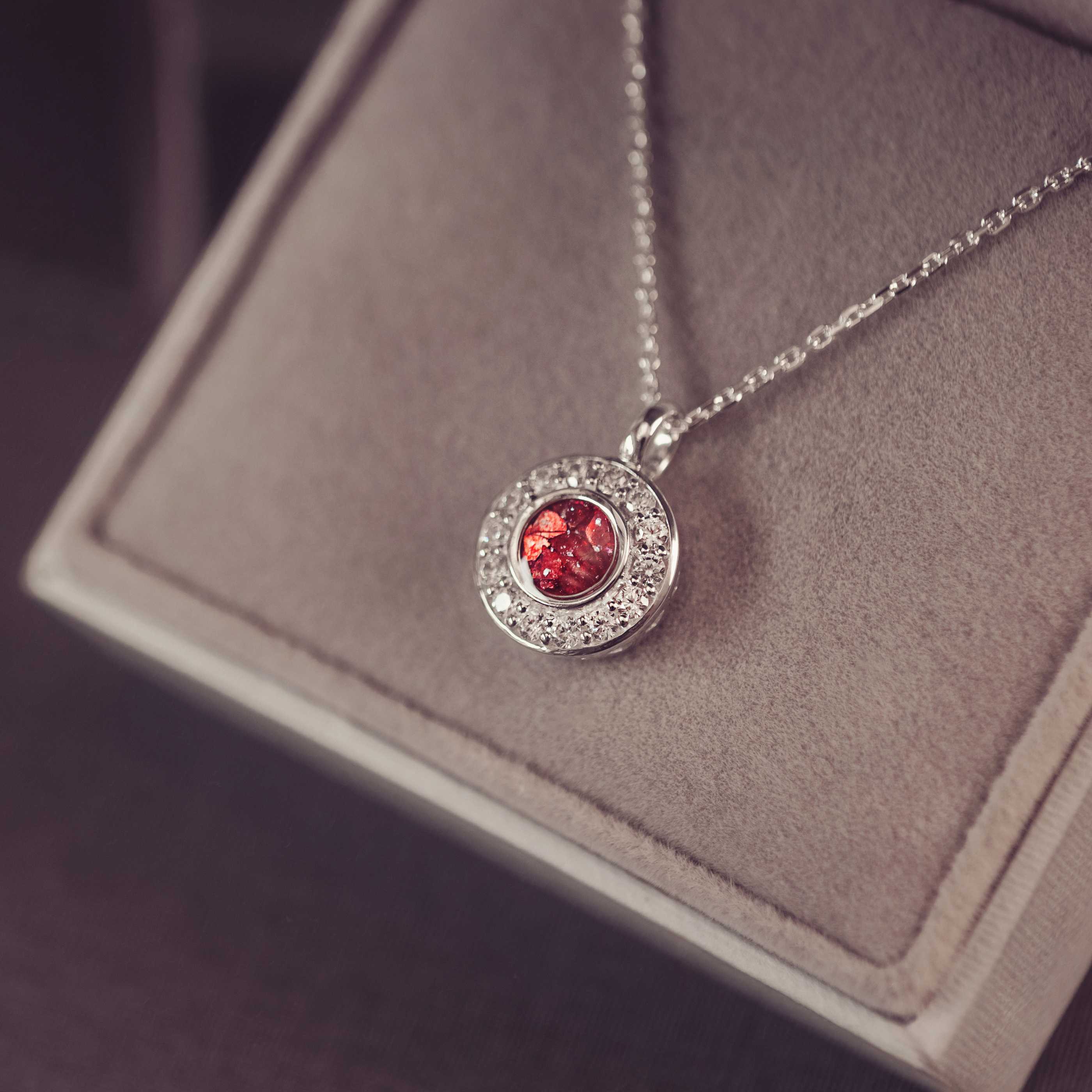 Silver necklace with a red gemstone pendant on a gray surface