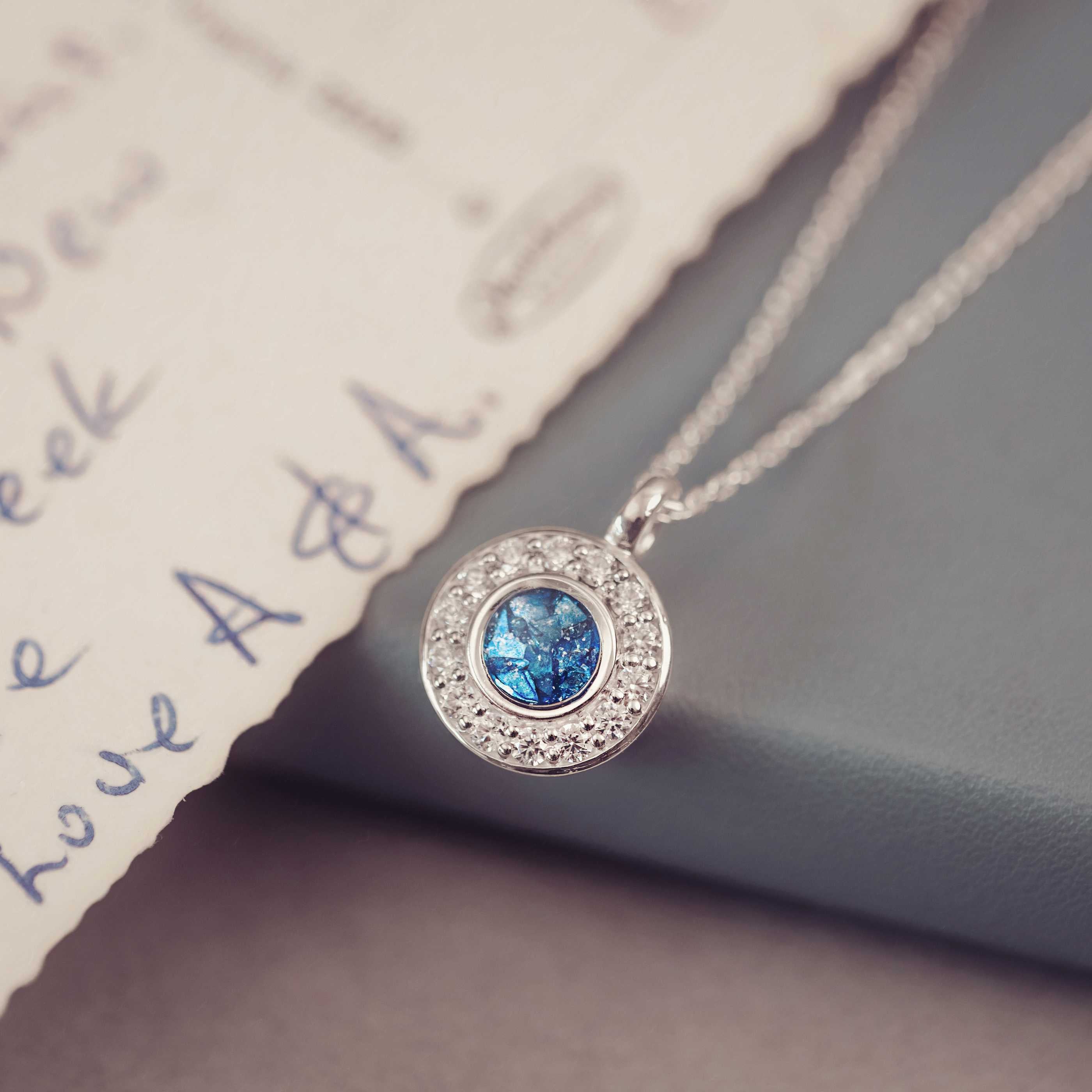 Silver necklace with a blue gemstone pendant on a textured surface