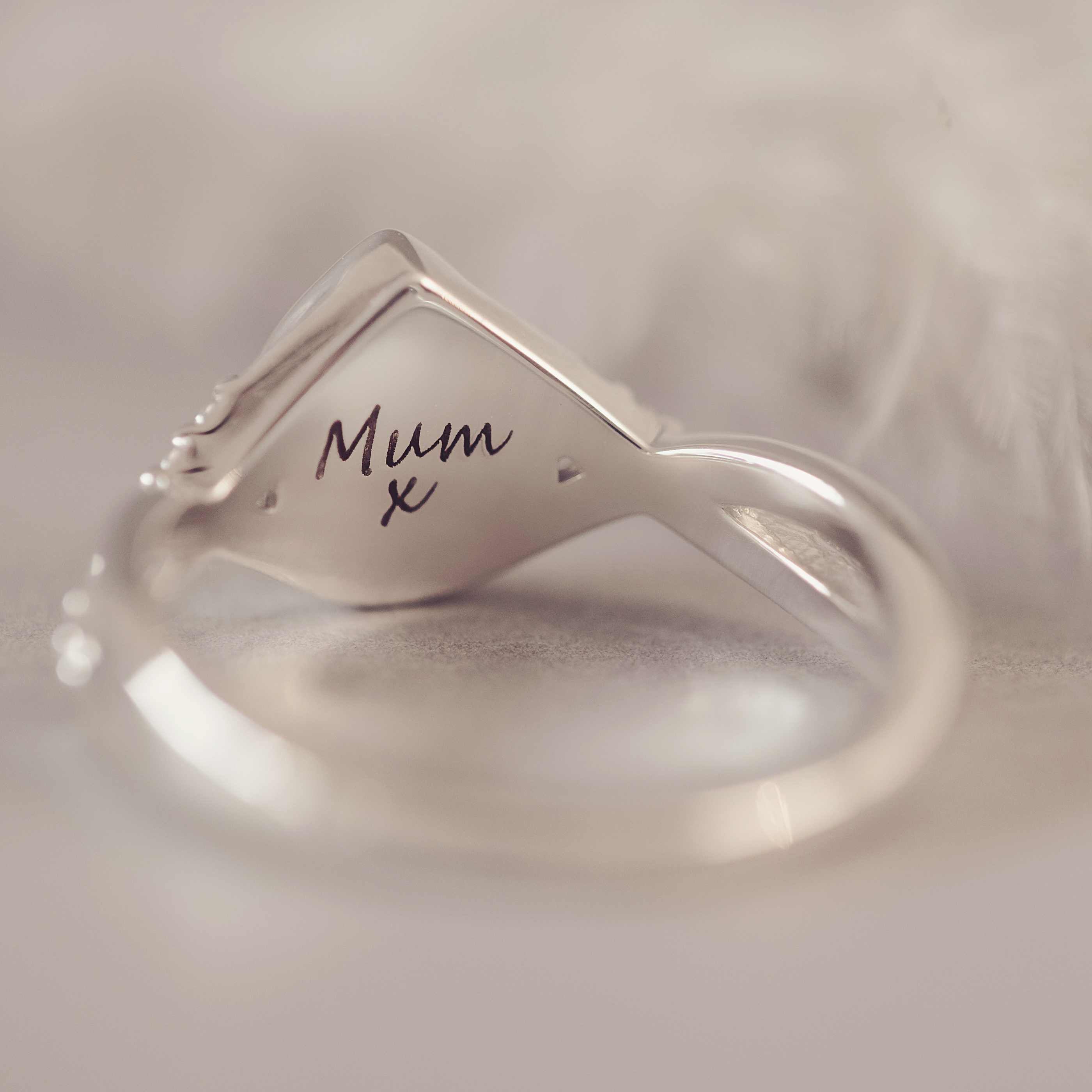 Silver ring with 'Mum x' engraving on a soft beige background