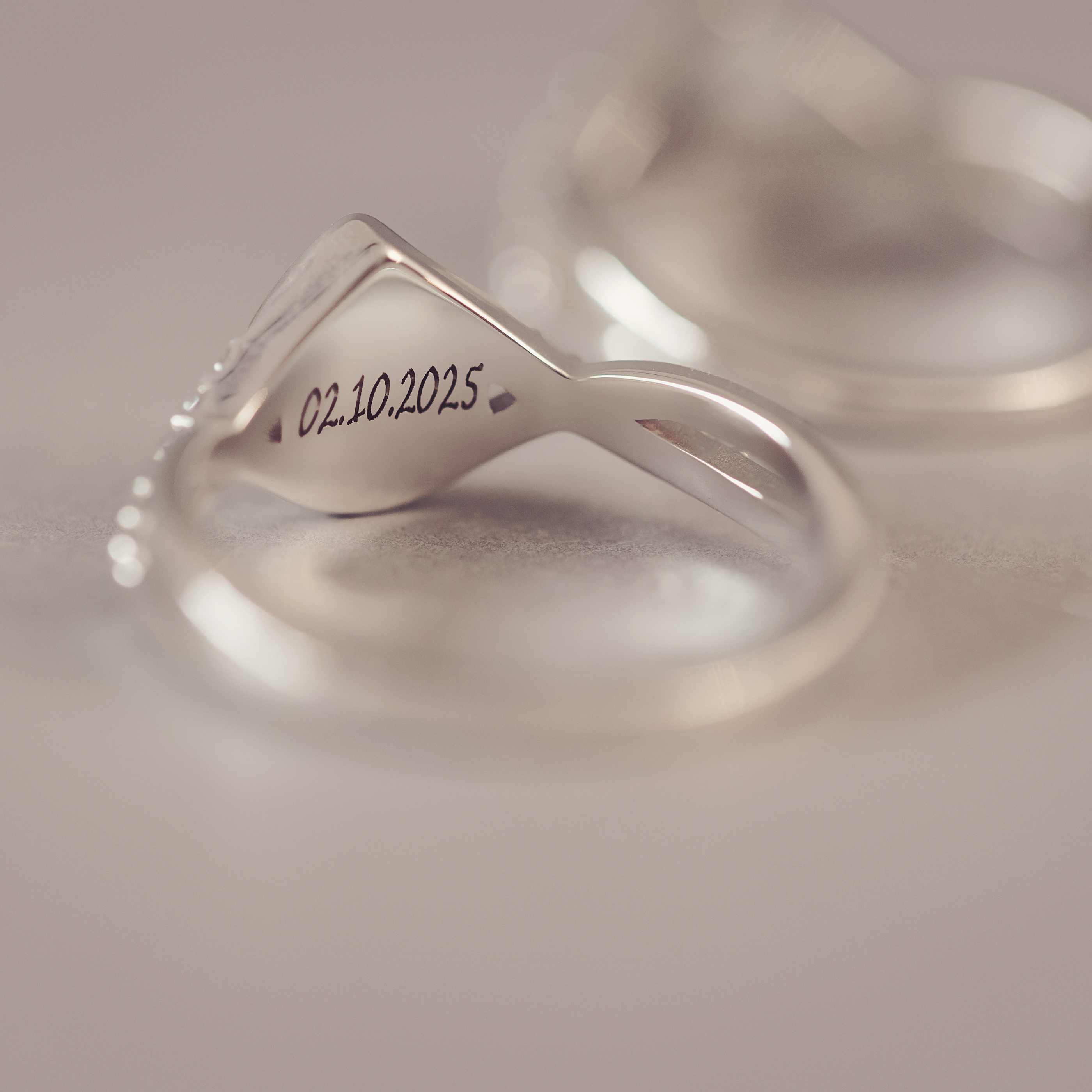 Silver infinity ring with engraved date on a soft white background
