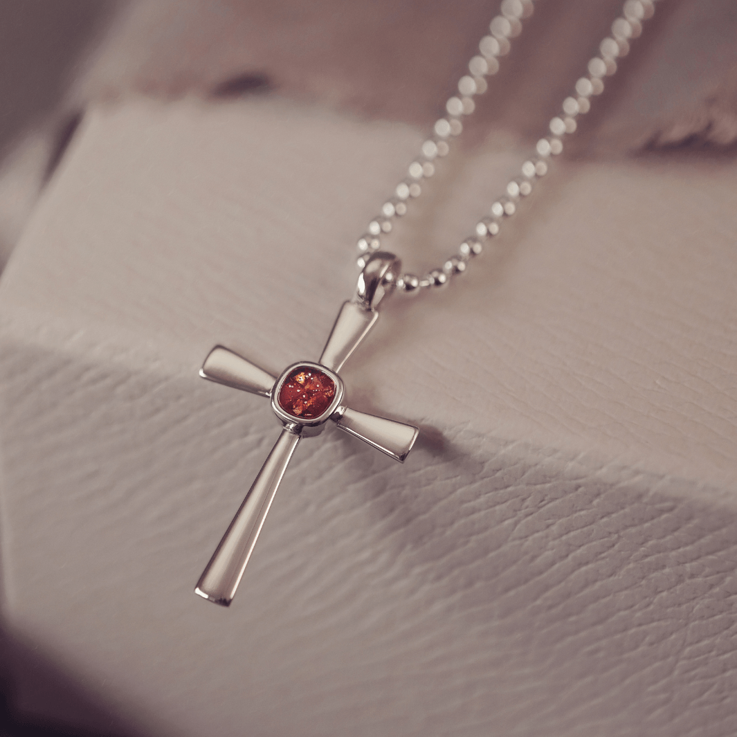 silver cross necklace holding cremation ashes, resin and orange crystal