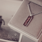 A sophisticated Mens silver necklace featuring a rectangular pendant filled with shimmering brown crystal and resin, delicately layered with cremation ashes, showcased against a dark background on a silver ball chain
