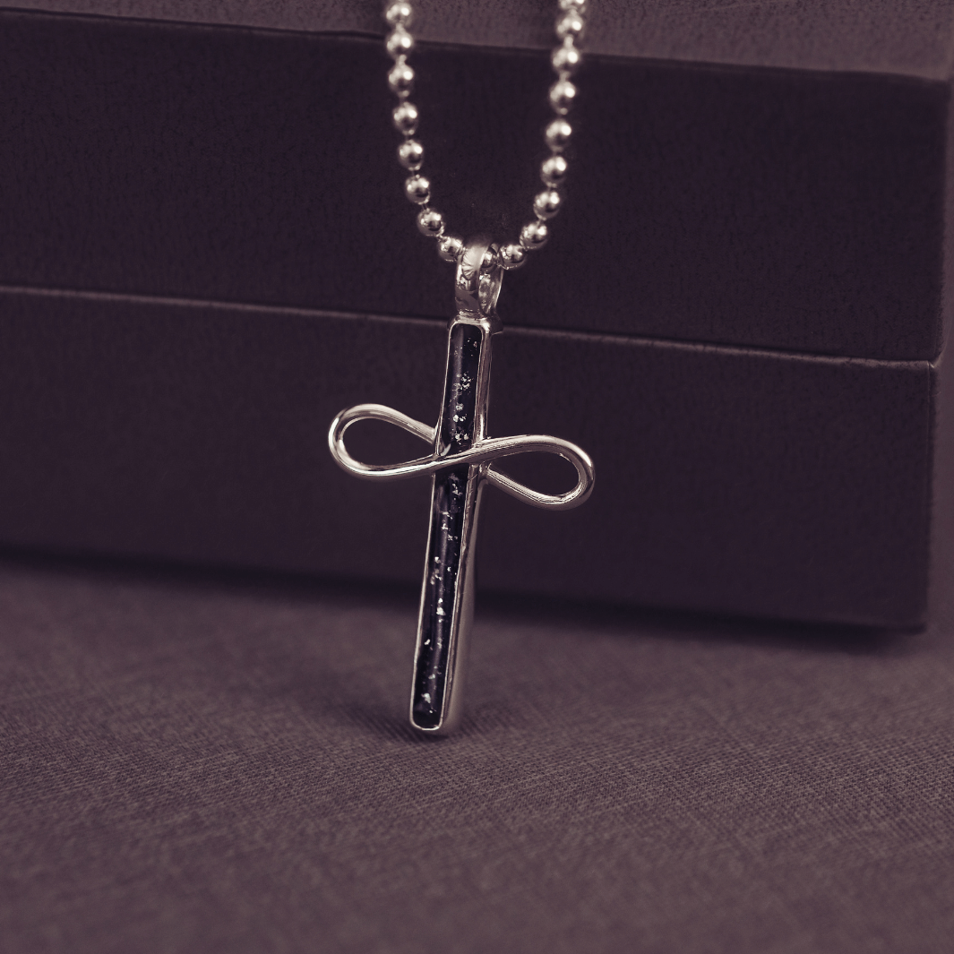 Silver cross pendant necklace on a dark background