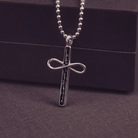 Silver cross pendant necklace on a dark background