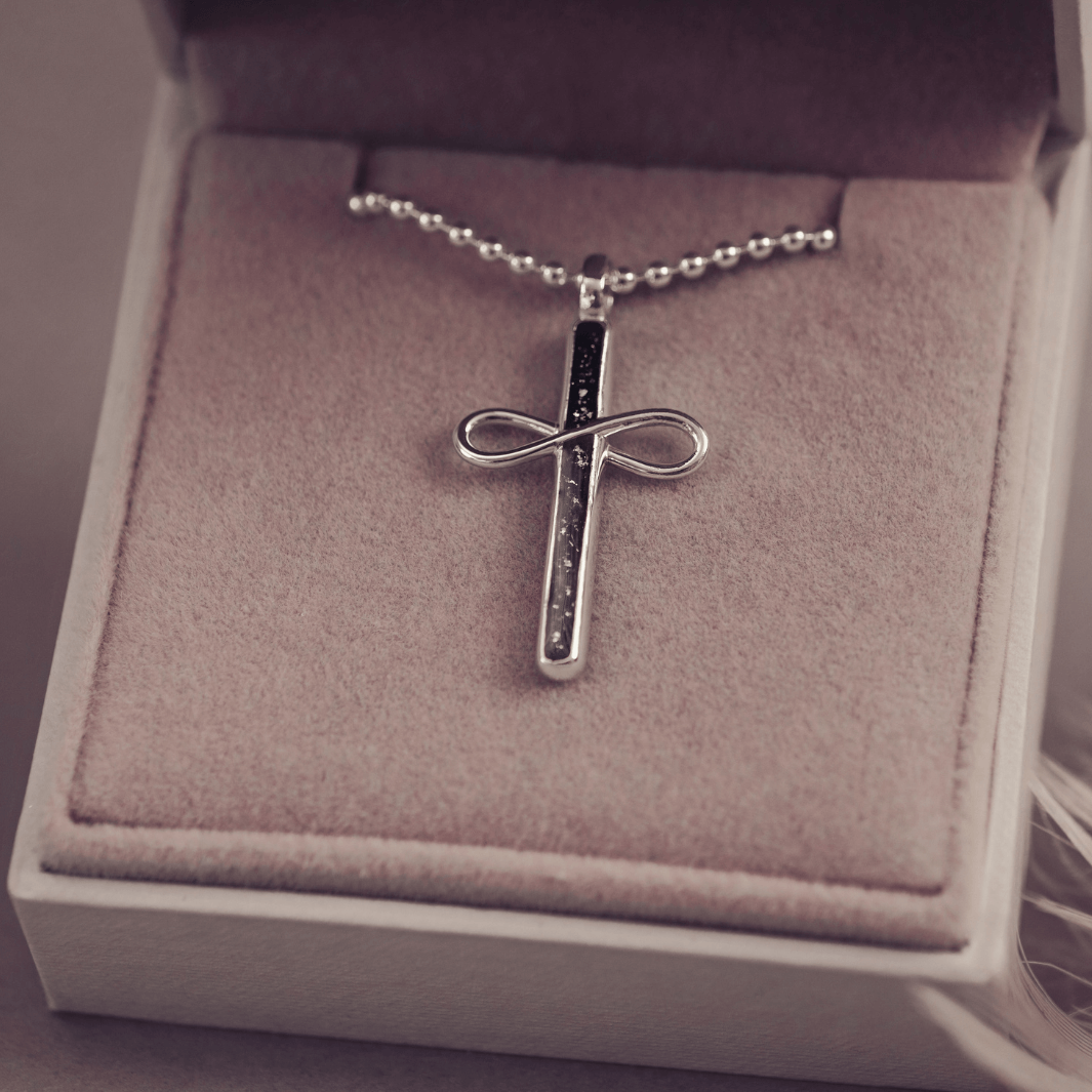 Silver cross necklace with chain on a cushion in a jewellery box