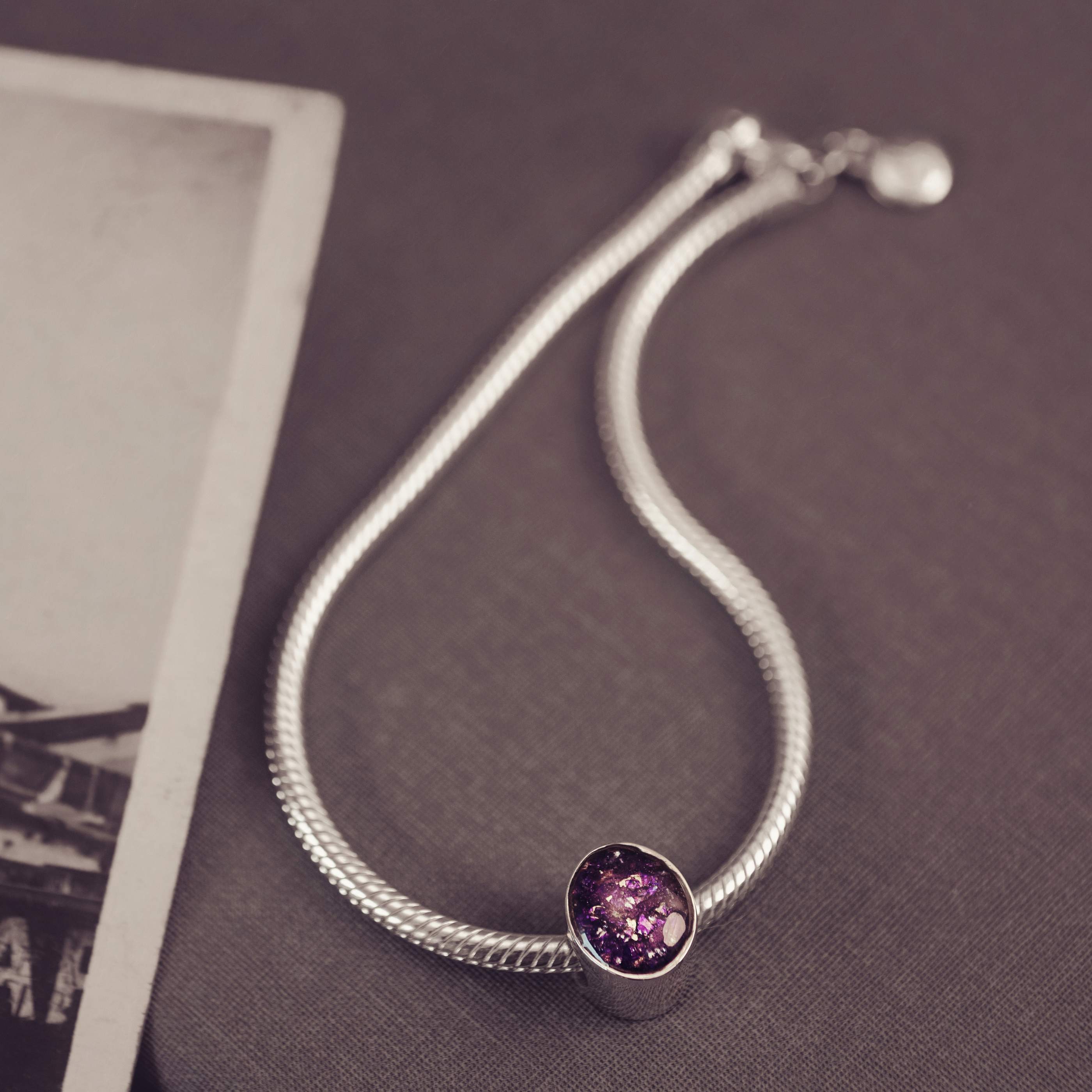 Silver bracelet with a purple gemstone on a textured surface