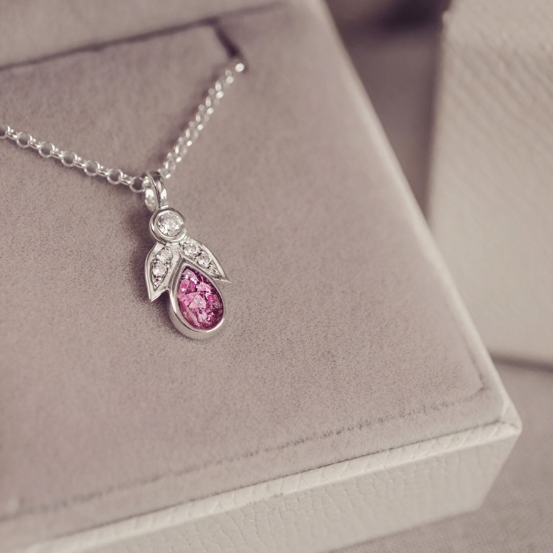 Silver necklace with a pink gemstone pendant on a soft gray background