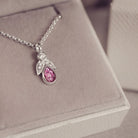 Silver necklace with a pink gemstone pendant on a soft gray background