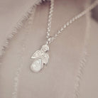 sterling silver angel pendant with clear floating crystals sat on a cream fabric 