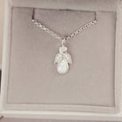 sterling silver angel pendant with clear floating crystals sat in a grey jewellery box 