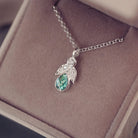 sterling silver angel pendant with green floating crystals sat in a jewellery box 