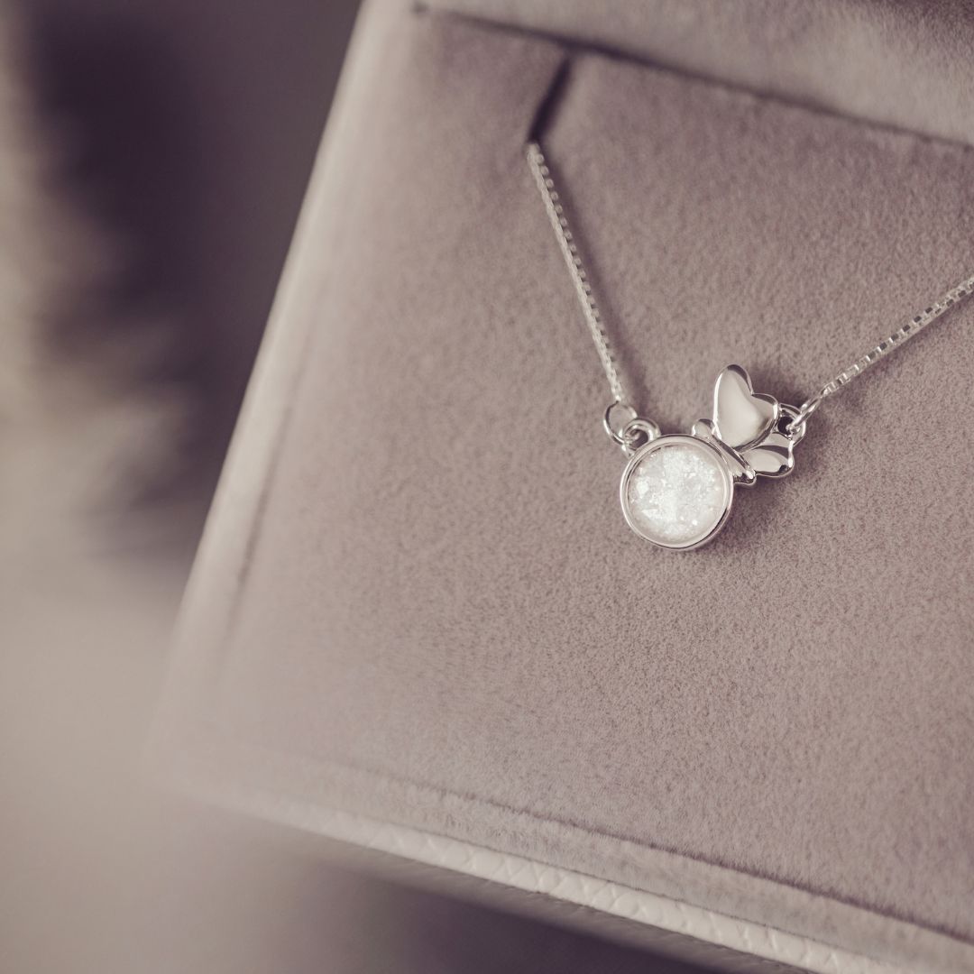 Silver necklace with a butterfly pendant on a soft fabric background