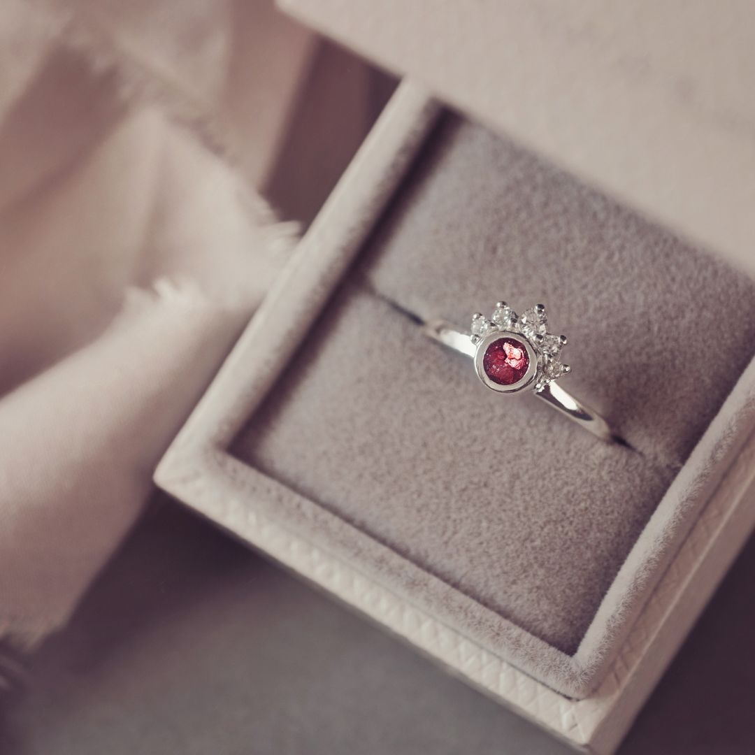 Silver ring with a red gemstone in a jewelry box