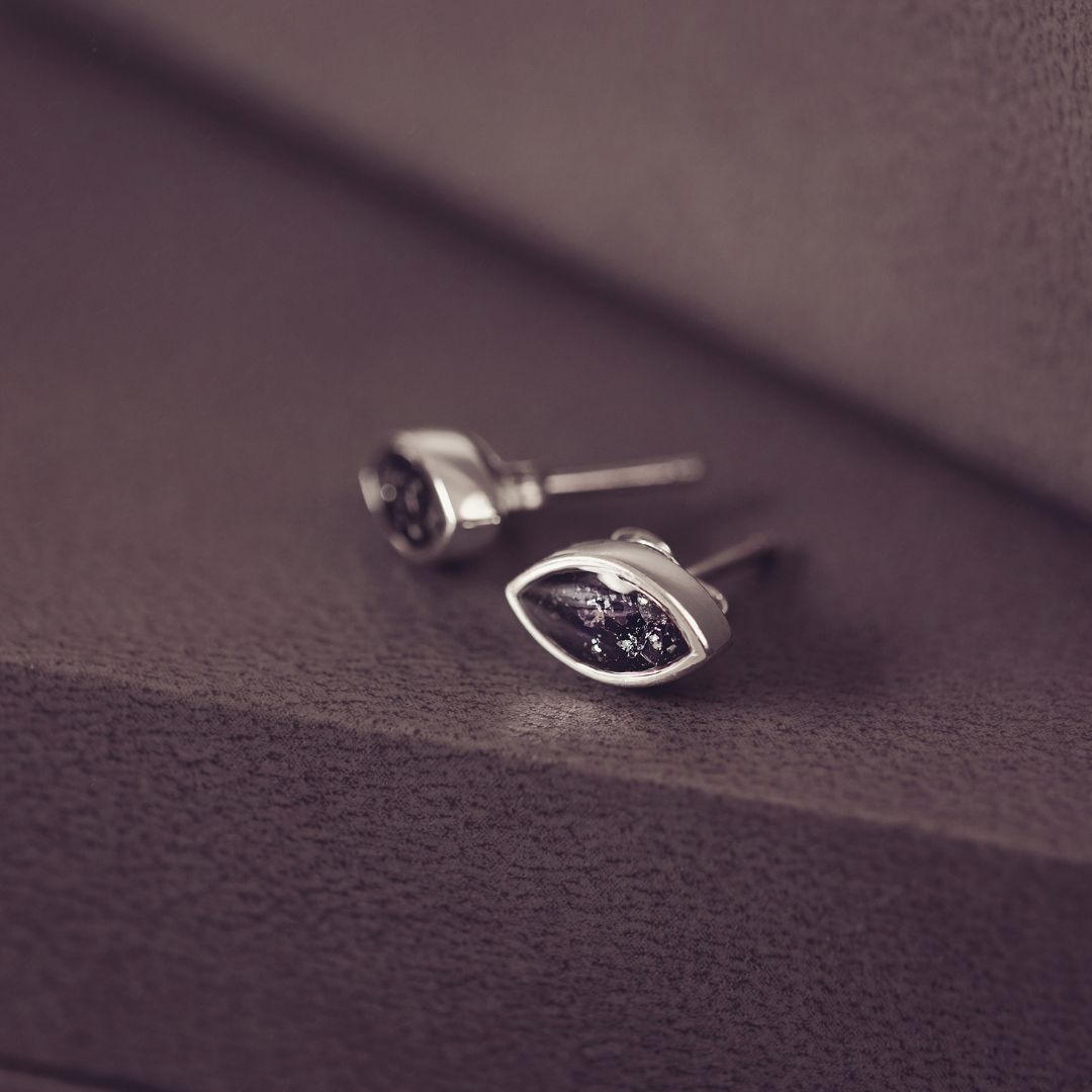 Silver earrings with purple gemstones on a textured purple surface