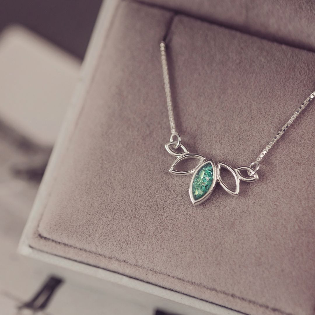 Silver necklace with a green gemstone pendant on a soft surface