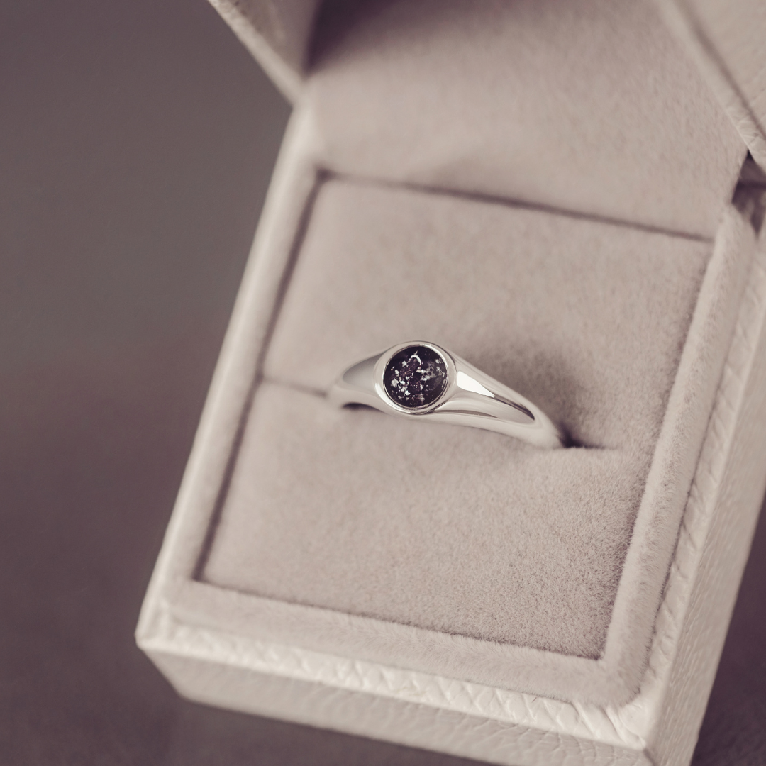 Silver ring with a purple gemstone in a jewelry box