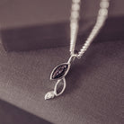 sterling silver necklace featuring gem stone, cremation ashes, black crystal and resin hung over a grey box