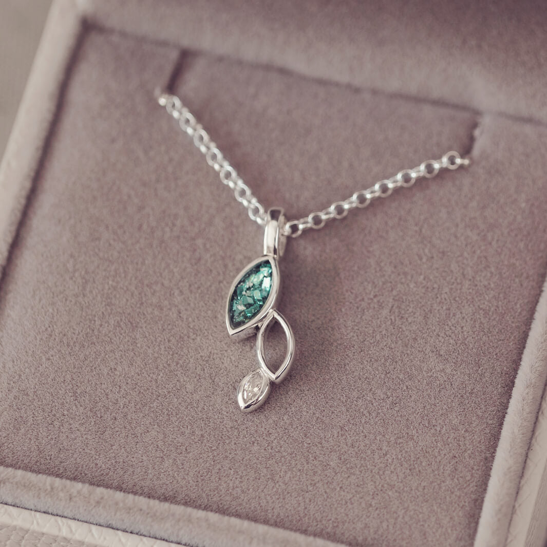 sterling silver necklace featuring gem stone, cremation ashes, green crystal and resin sat in a grey jewellery box 