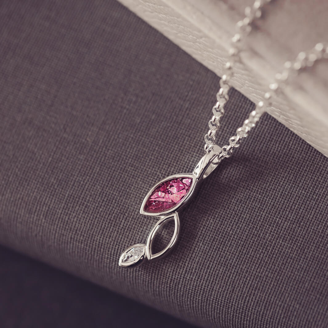 sterling silver necklace featuring gem stone, cremation ashes, pink crystal and resin sat on a grey back ground 