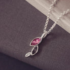 sterling silver necklace featuring gem stone, cremation ashes, pink crystal and resin sat on a grey back ground 