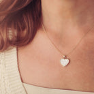 gold heart necklace filled with clear crystals, resin and cremation ashes, worn on a gold chain around a ladies neck