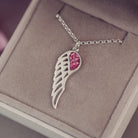 Silver Angel Wing Necklace with pink floating crystals which hold cremation ashes. Shown in a grey jewellery box 