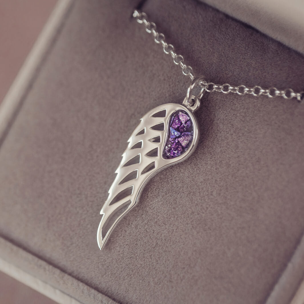 Silver Angel Wing Necklace with purple floating crystals which hold cremation ashes. Shown in a grey jewellery box 