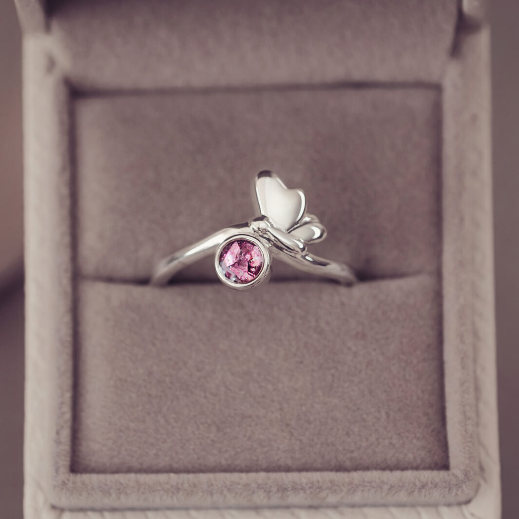 Silver butterfly ring with pink crystals and cremation ashes in a grey jewellery box 
