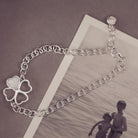 sterling silver chain bracelet with clover shaped charm holding clear crystal and cremation ashes sat on top of a black and white photo 