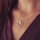 A silver heart-shaped pendant necklace featuring two sparkling resin stones, holding cremation ashes, worn on a ladies neck