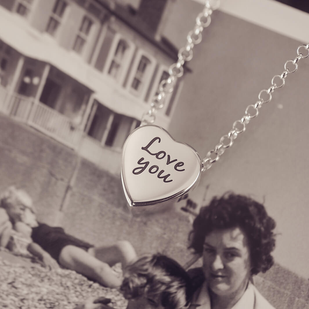 Silver heart pendant on a silver chain with the message 'Love you' engraved on the reverse