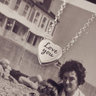 Silver heart pendant on a silver chain with the message 'Love you' engraved on the reverse