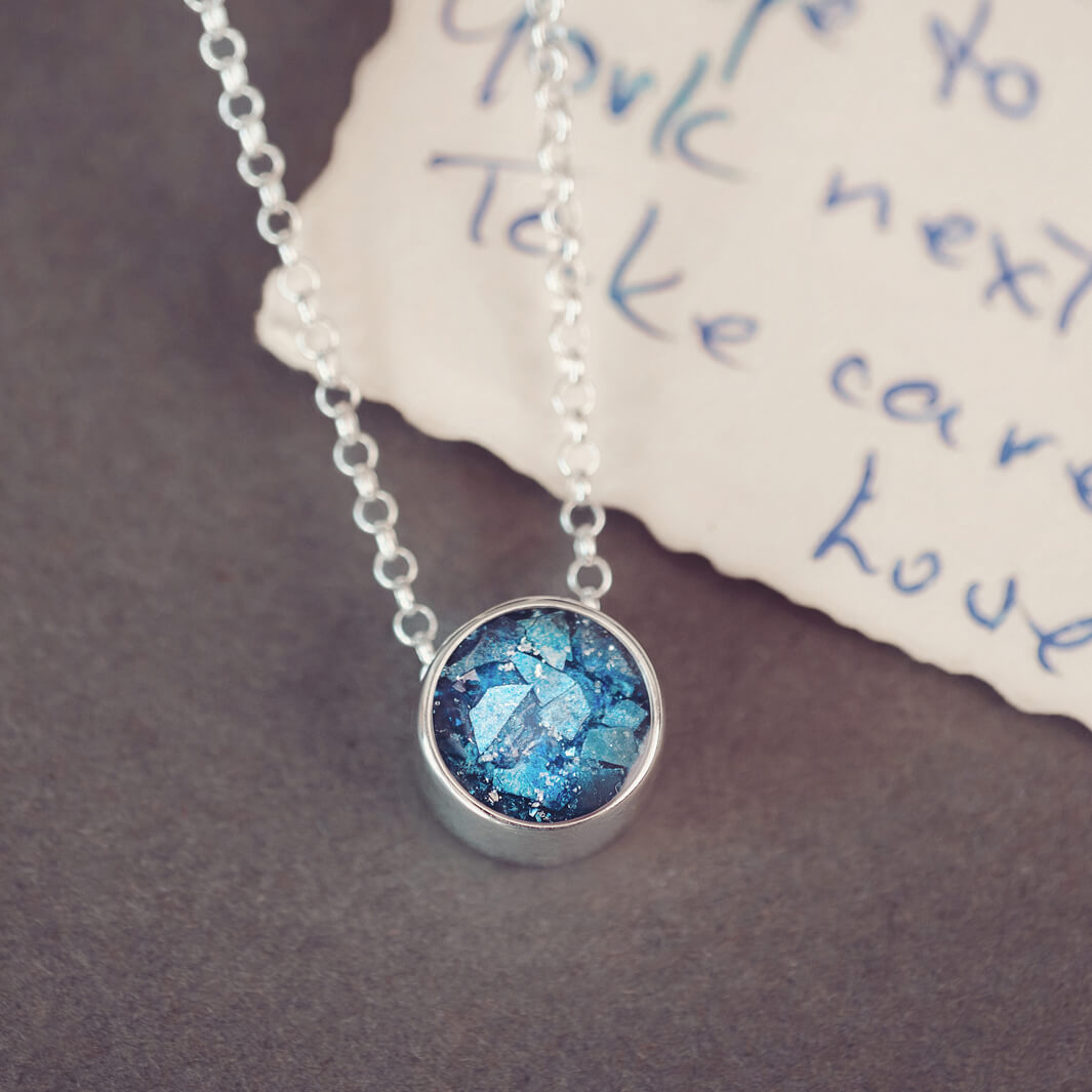 Round silver charm on silver chain, filled with blue crystal, glitter, resin & ashes. 