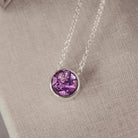 Round silver charm on silver chain, filled with purple crystal, glitter, resin & ashes. 